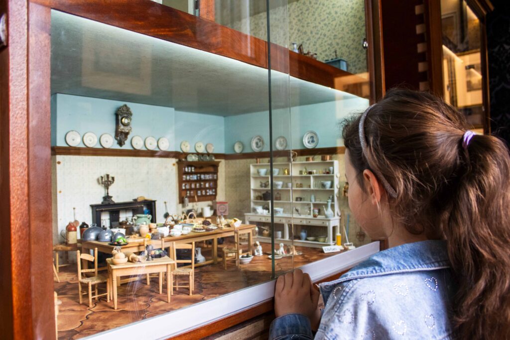 A young girl looks into a beautiful giant doll's house.